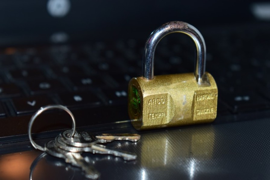 Photo of a padlock and keys with a laptop in the background.